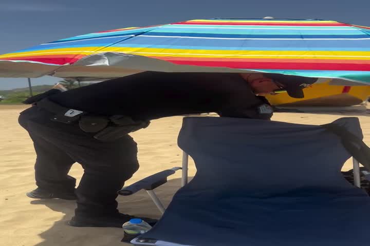 Video: Policía en PR le monta la sombrilla de playa que se le fue volando a ciudadana